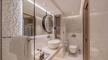 A modern bathroom with a large white sink, a round mirror, and a toilet.