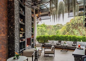 Un interior modern amb una paret de pedra, una llar de foc i una zona de seients amb vista a vegetació exuberant.