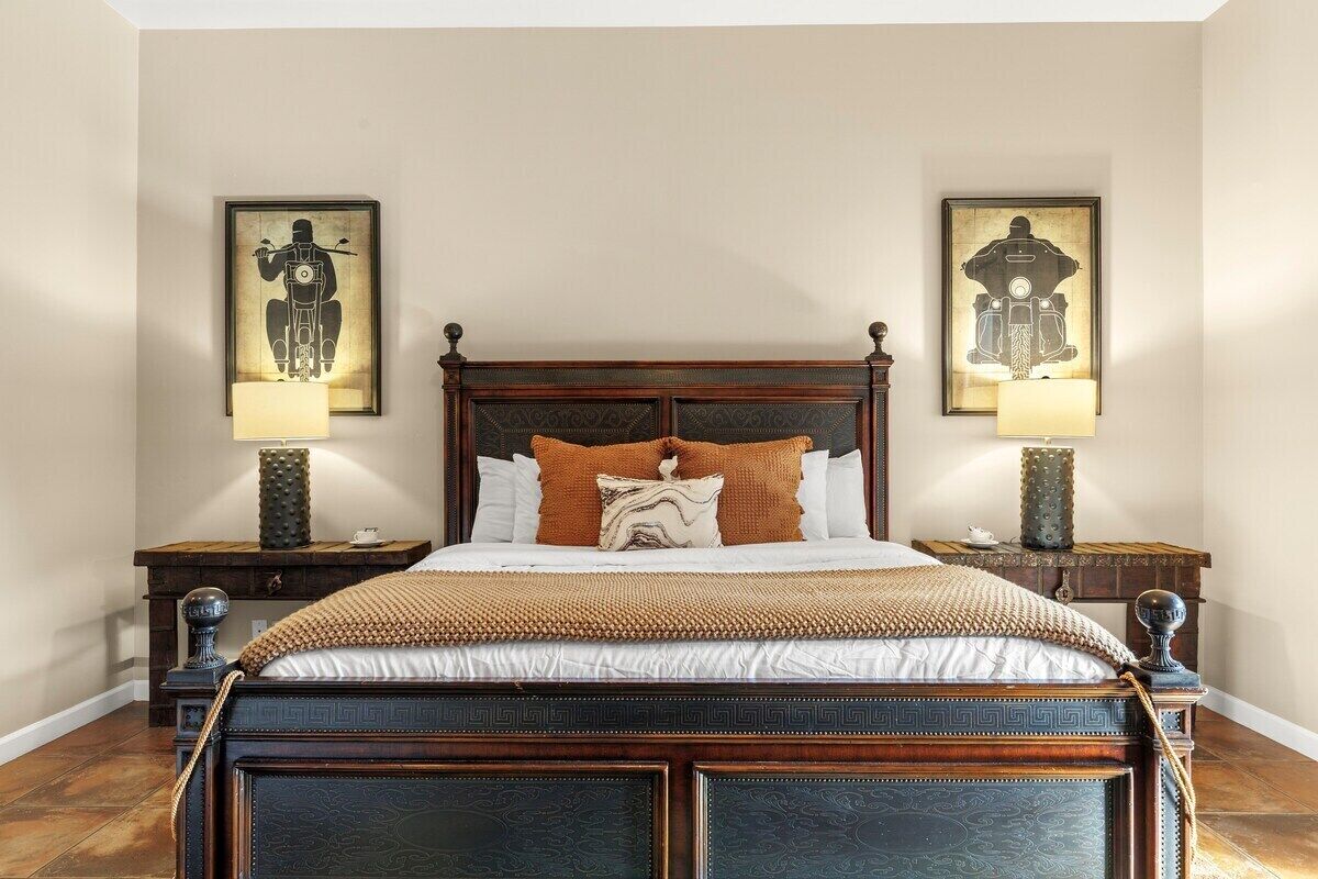 A large bed with a dark wooden headboard, flanked by two nightstands with lamps.