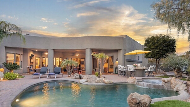 Une maison moderne dotée d’une piscine, d’un espace salon extérieur et d’un patio.