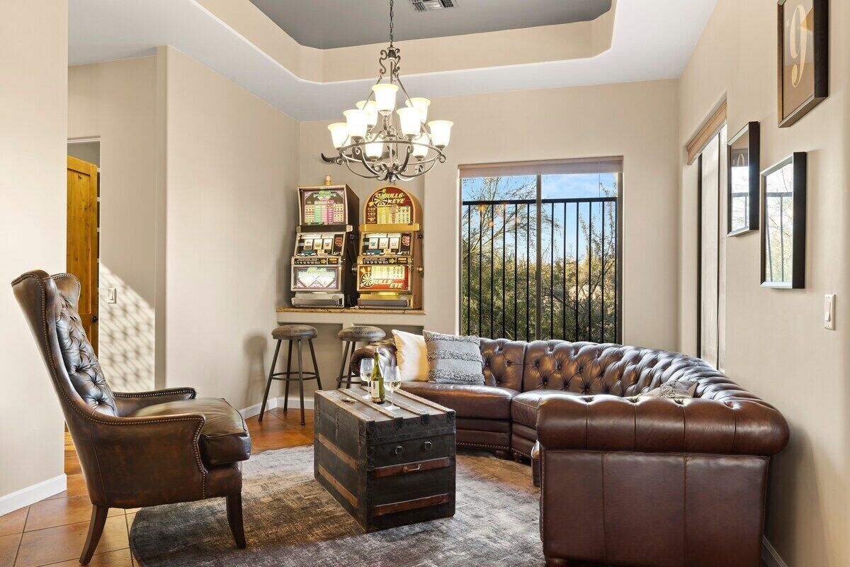 A living room with a leather sofa, a tufted armchair, a coffee table, and a chandelier.