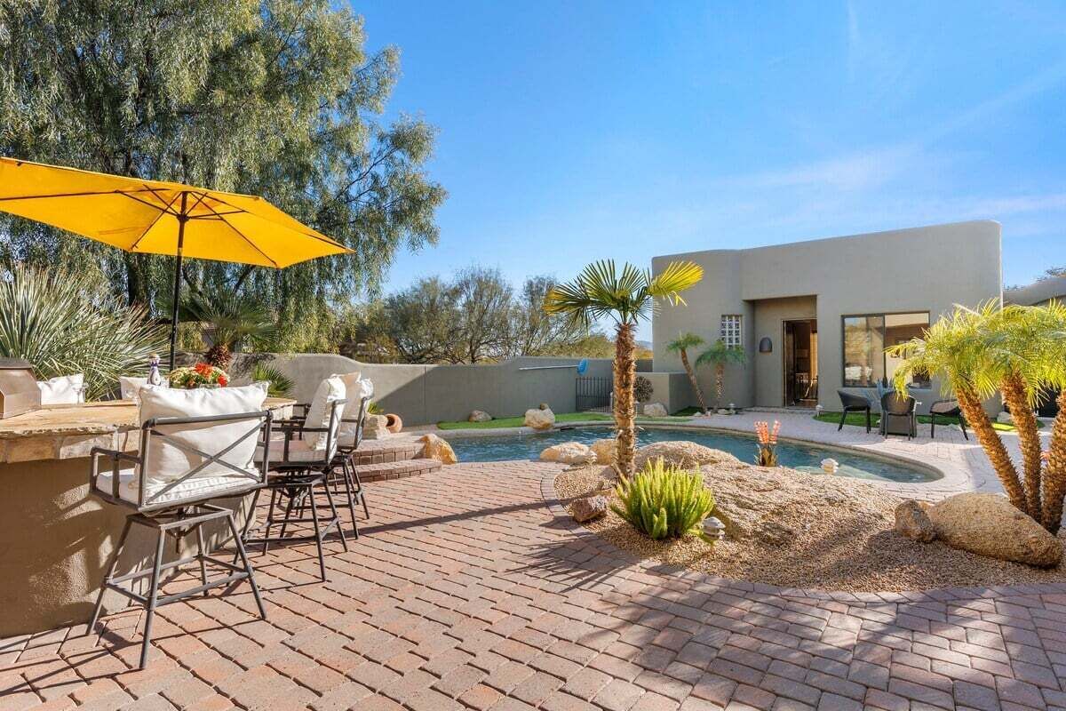 Un patio con mobiliario exterior, una piscina y un edificio moderno al fondo.