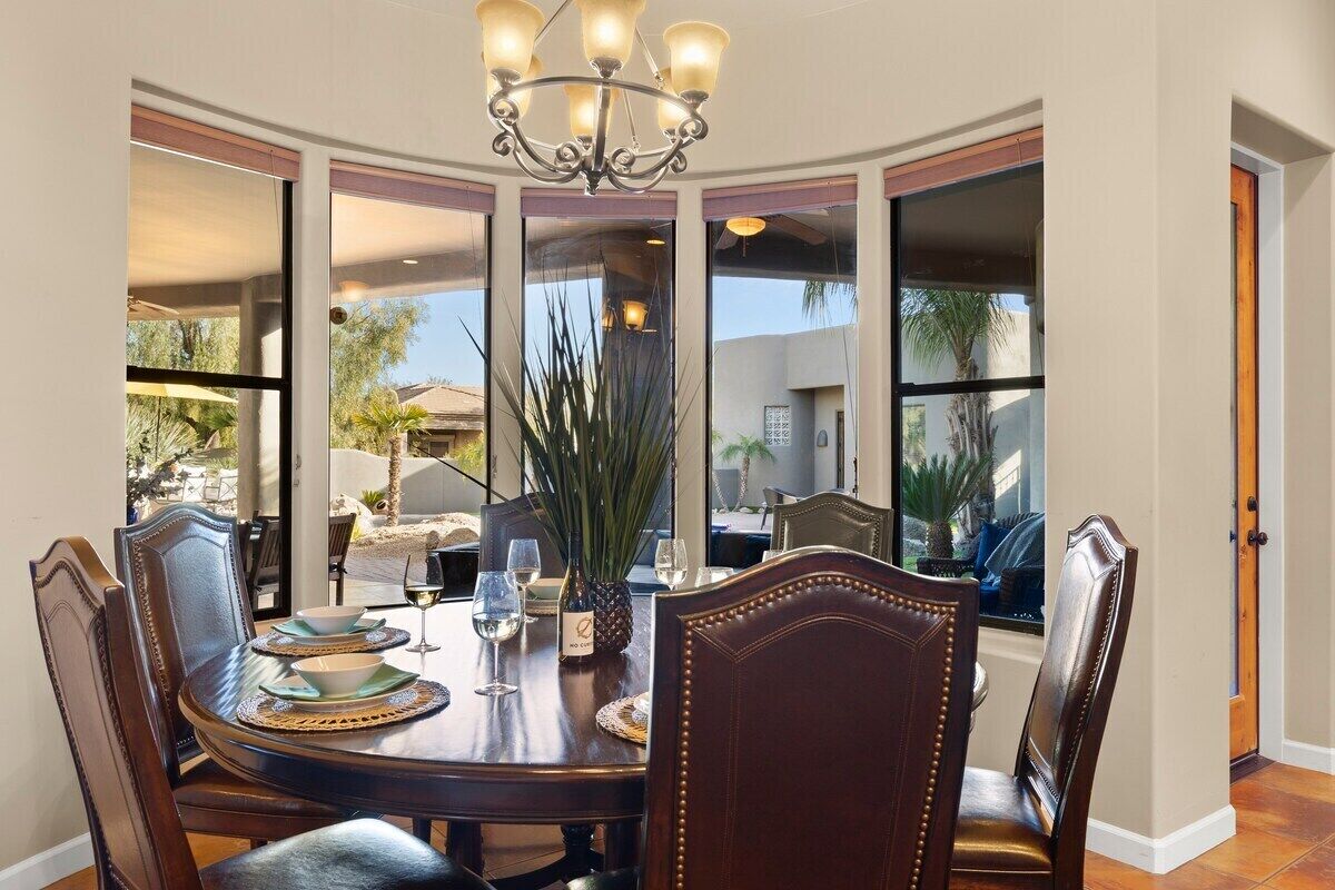 A dining area with a round table, chairs, and a chandelier.