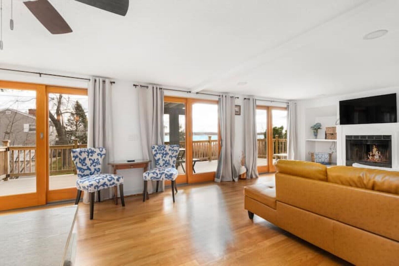 A spacious living room with a wooden floor, a yellow sofa, and patterned chairs.