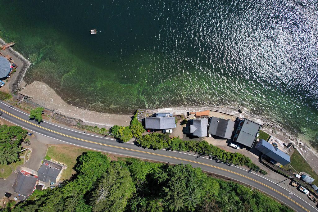 An aerial view of a coastal area with a road, buildings, and a body of water.