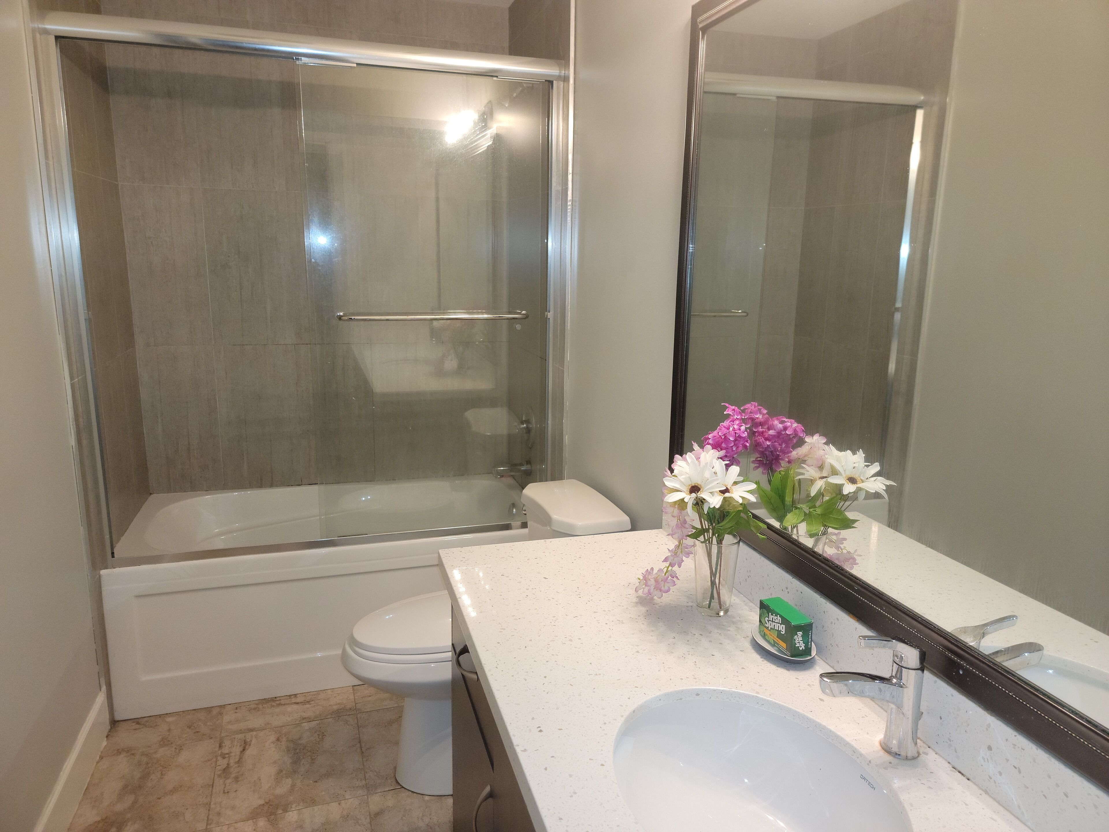 Un baño con ducha envuelta en cristal, inodoro y lavabo con espejo.