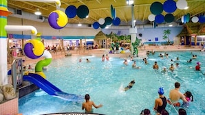 An indoor swimming pool with multiple lanes, a water slide, and various play structures.