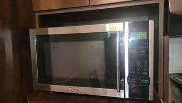 A microwave oven with a digital display, control panel, and brand logo.