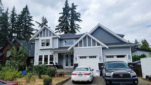 A two-story house with a garage, a driveway, and two parked cars.