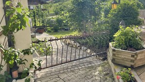 Een tuin met een metalen hek, bloembakken en een houten plantenbak.