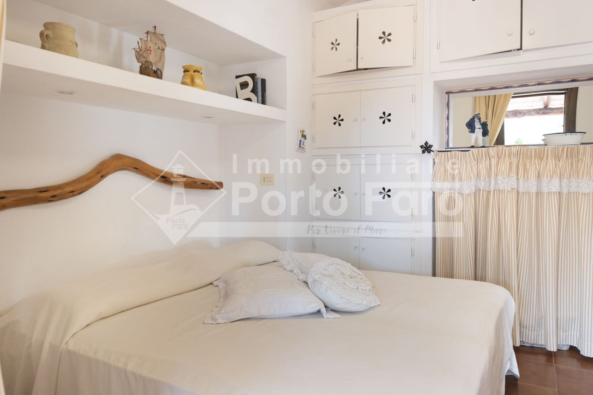 Camera da letto con un letto, tende bianche e una testiera in legno.