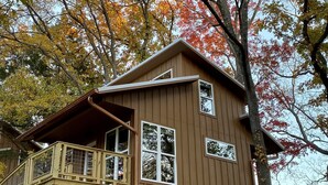 A wooden cabin with a balcony, surrounded by trees with autumn foliage. - Coach's Quarters - The Dugout - Come Spend The Night in the Trees!! (Waco)
