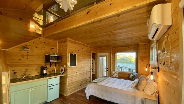 A wooden cabin with a kitchen, a bed, and a bathroom. - Coach's Quarters - The Dugout - Come Spend The Night in the Trees!! (Waco)