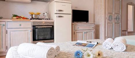 Ein Hotelzimmer mit Bett, Fernseher, Kühlschrank, Herd und einem Holzschrank.