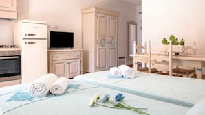 A hotel room with a bed, a TV, a wardrobe, and a desk with a plant. - Le Residenze Del Golfo Di Orosei Bilo 5 (Orosei)