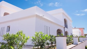 A white building with arched windows and a balcony, surrounded by greenery. - Le Residenze Del Golfo Di Orosei Bilo 5 (Orosei)