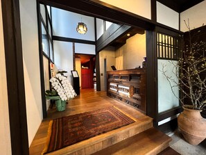 A traditional Japanese interior with tatami flooring, a wooden reception desk, and a hanging lantern. - Rinn Shiki Juraku (Kyoto)