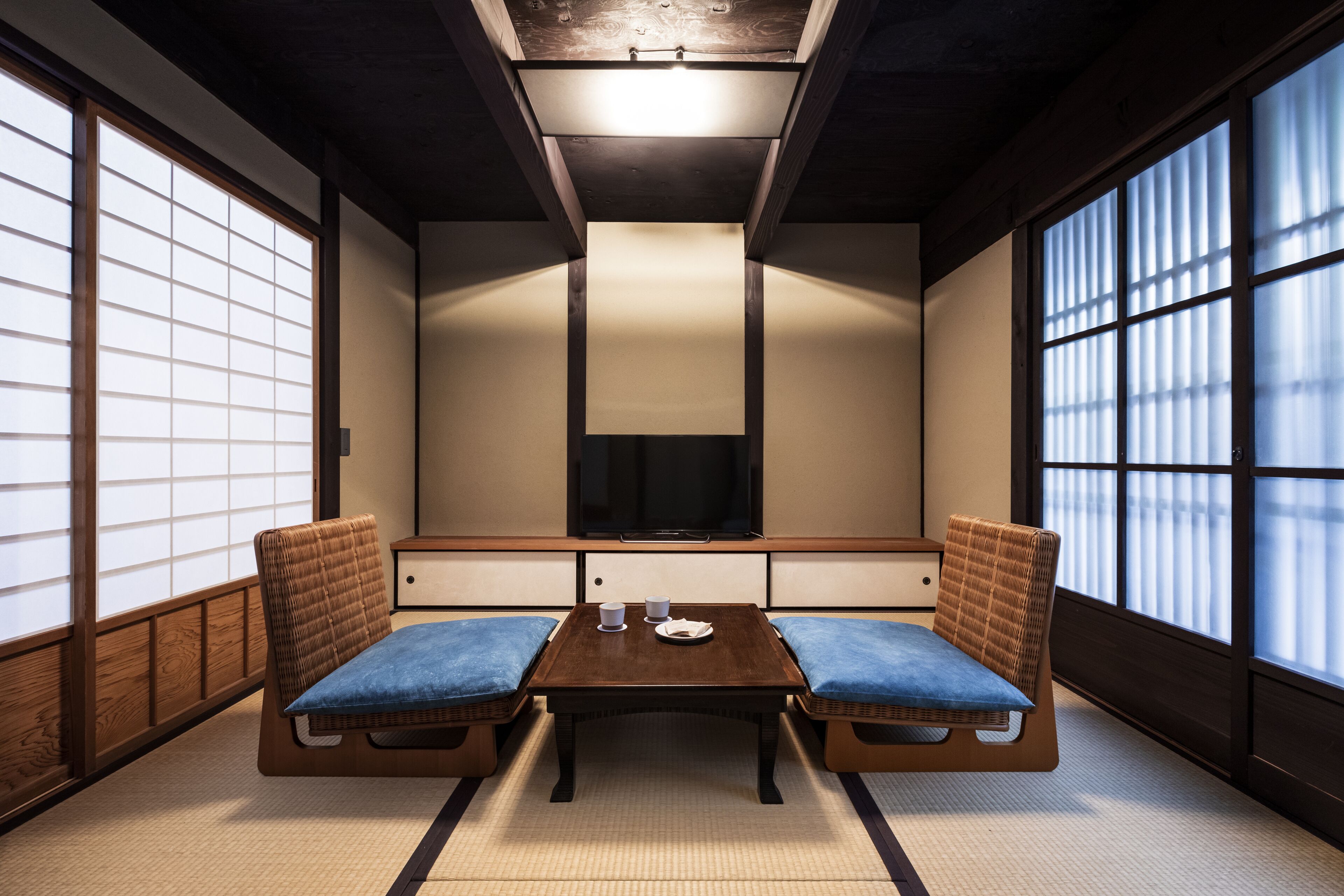 Een traditionele Japanse kamer met tatami vloerbedekking, een lage tafel en een televisie.