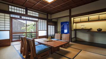 A traditional Japanese room with tatami flooring, a low wooden table, and a sliding door leading to an outdoor area.