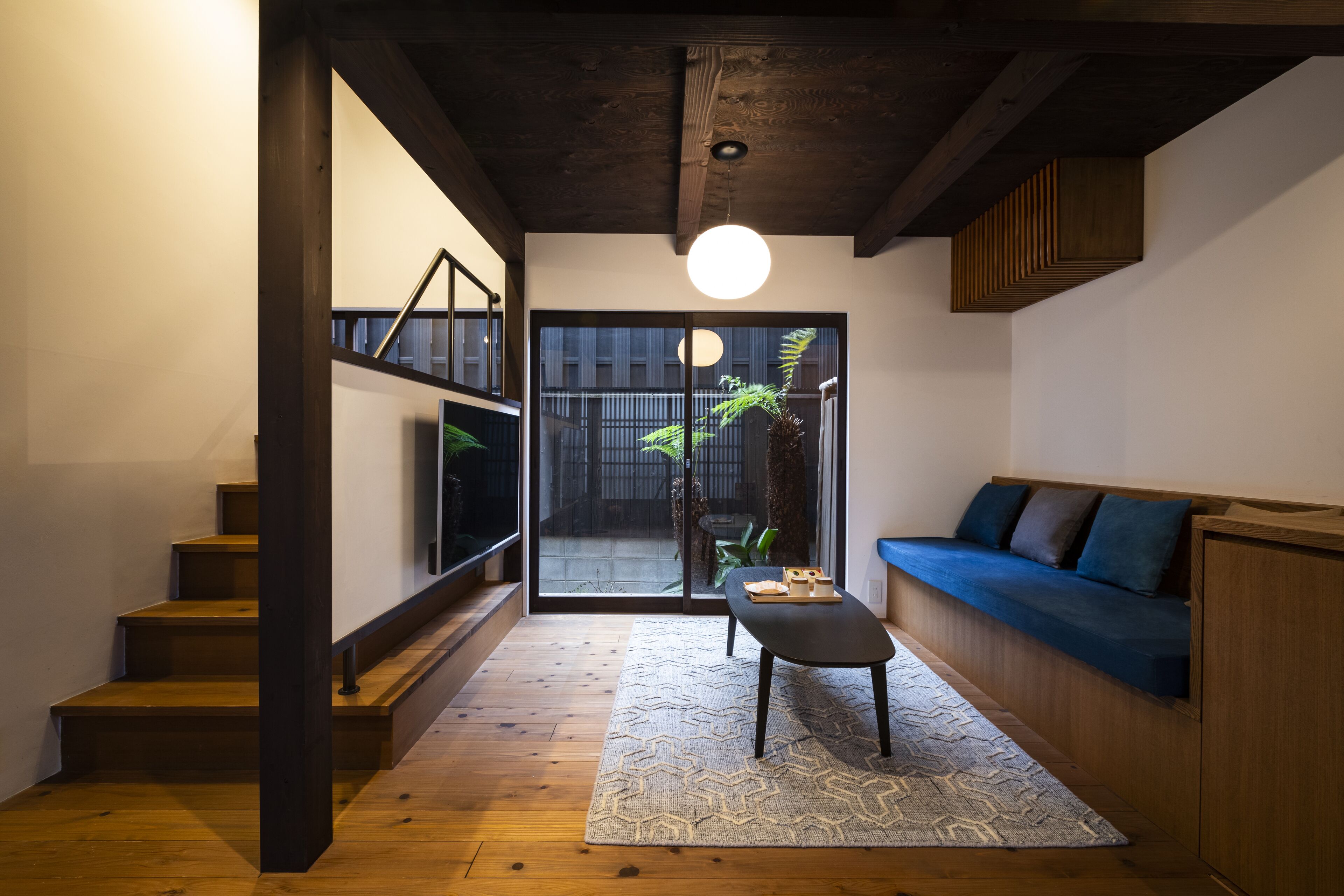 A modern interior with a staircase, a seating area, and a large window.