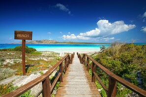 A wooden boardwalk leading to a beach with a sign that reads "BEACH". - Sea Villas (Stintino)