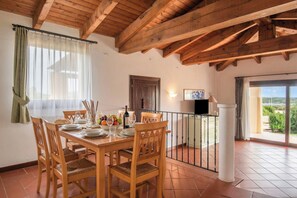 A dining area with a wooden table, chairs, and a view of the outdoors. - Sea Villas (Stintino)