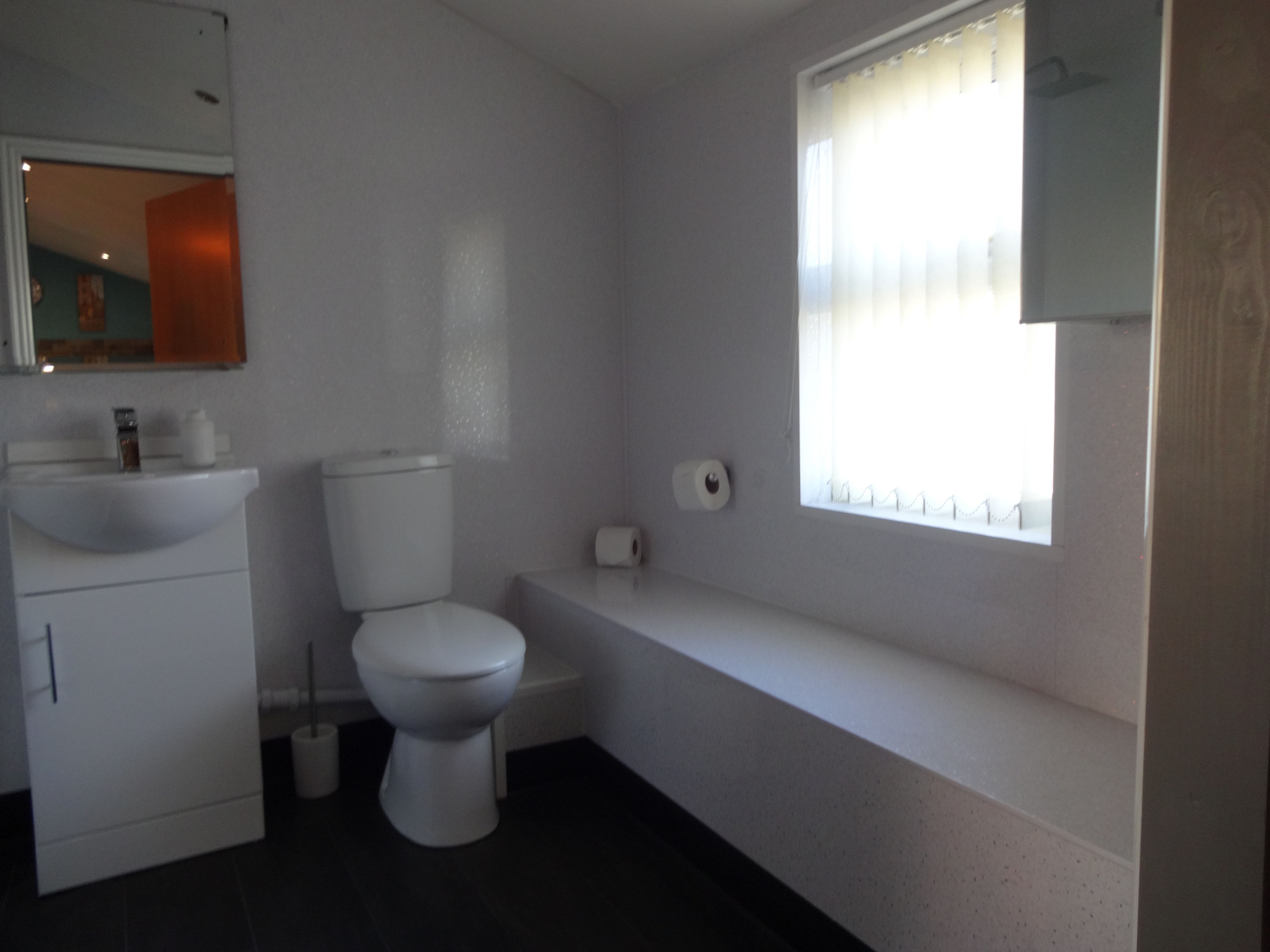 Een badkamer met toilet, wastafel en raam.