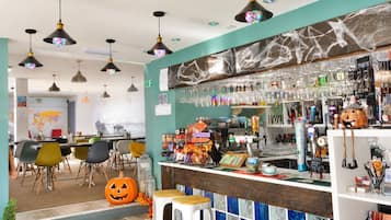 A bar area with stools, a counter with various items, and hanging lights.