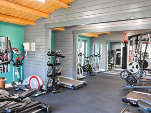 Un gimnasio con diverso equipamiento de ejercicio, incluyendo cintas de correr, bicicletas estáticas y máquinas de pesas.