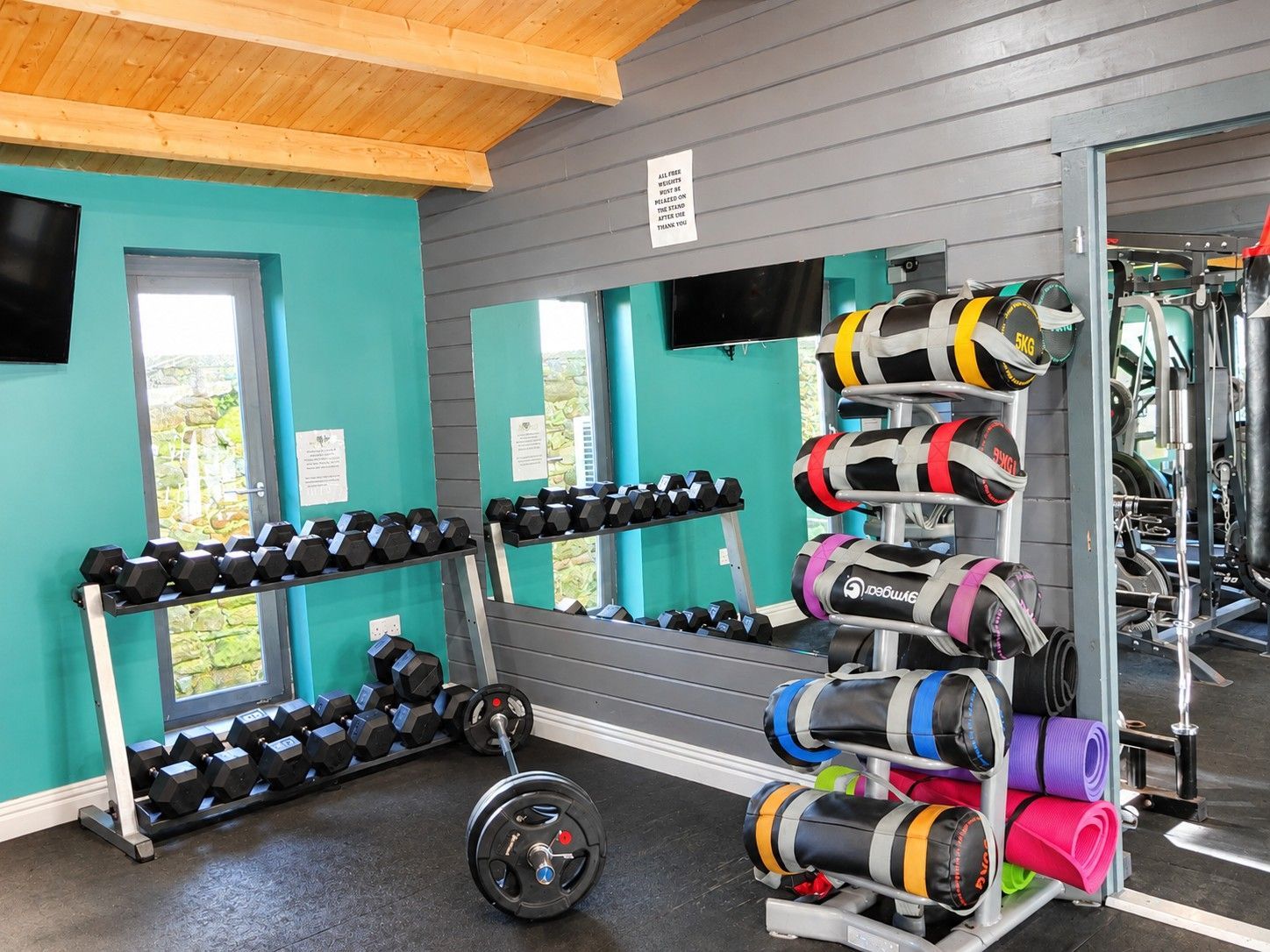 A gym with weightlifting equipment, including dumbbells, a barbell, and weight plates.