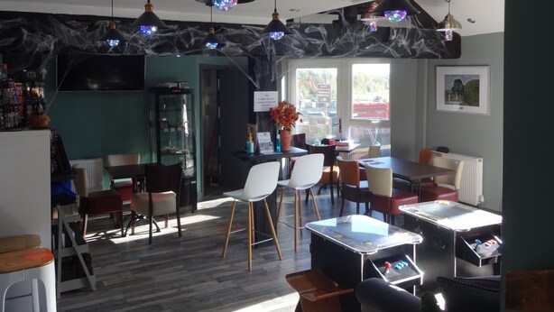 A modern restaurant interior with a bar area, seating arrangements, and a view of the outside.