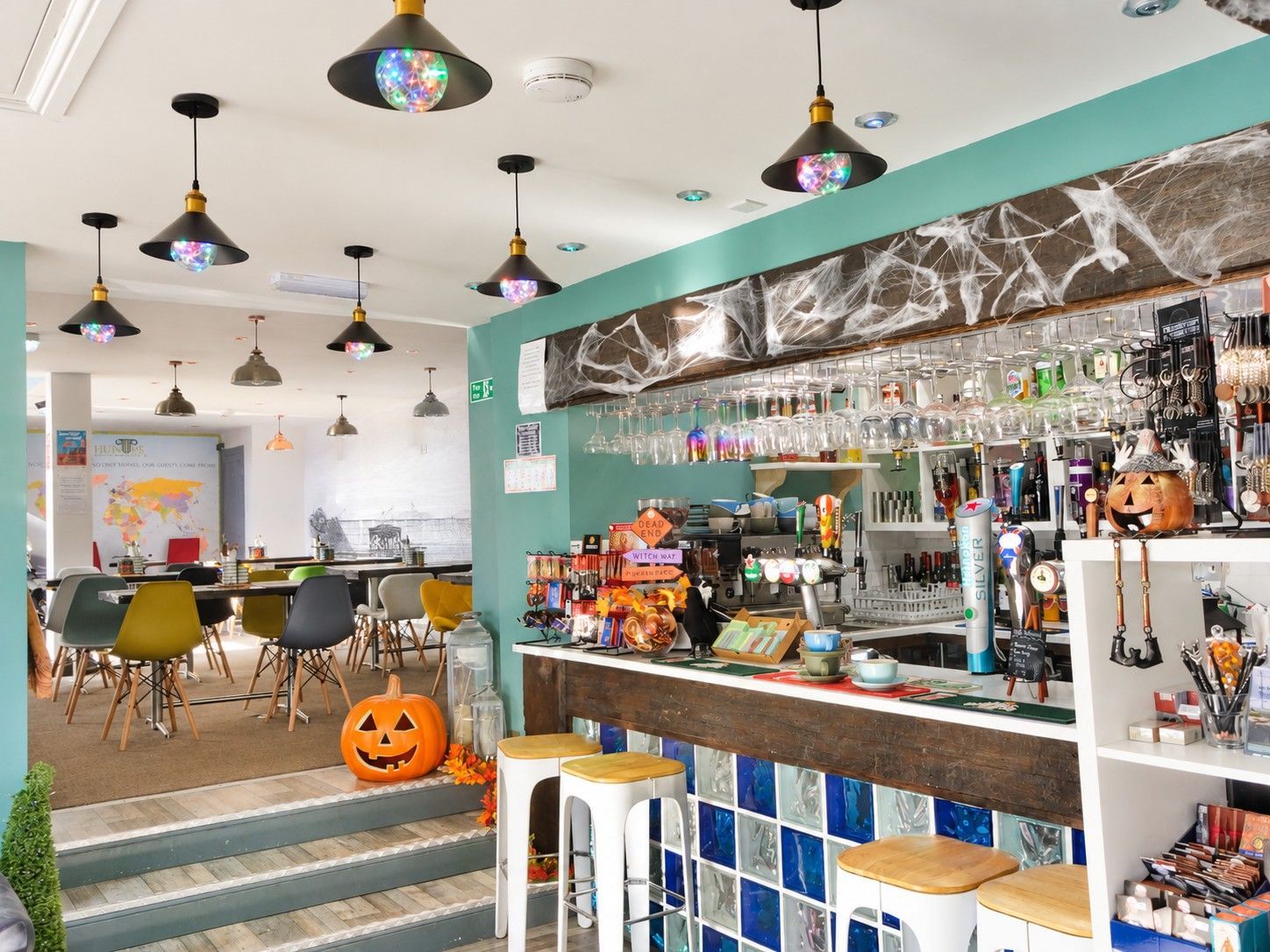 A bar area with stools, a counter with various items, and hanging lights.