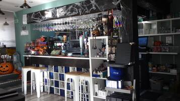 Un espace bar avec des tabourets, des étagères remplies de bouteilles et une décoration d’Halloween.