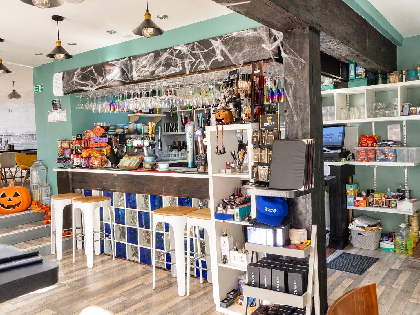A bar area with stools, shelves stocked with bottles, and Halloween decorations.