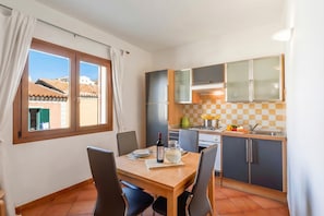 Uma cozinha compacta com mesa, cadeiras e janela com cortinas.