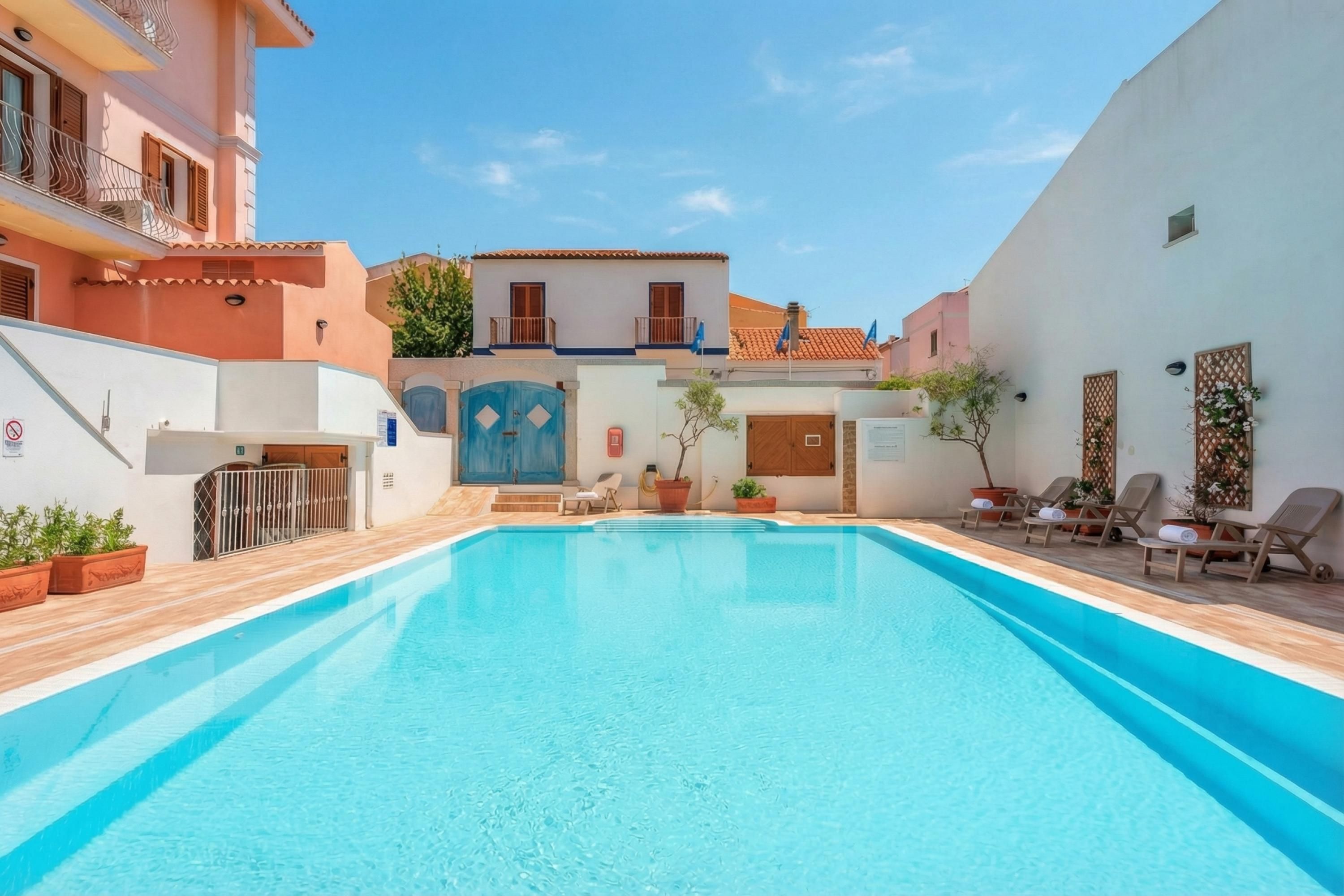 Piscina com deck de madeira, portão azul e plantas em vasos.