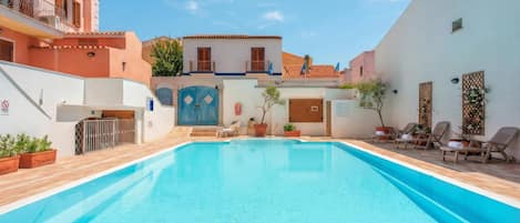 Una piscina con cubierta de madera, una reja azul y plantas en macetas.