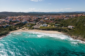Uma cidade costeira com praia, edifícios e montanhas ao fundo.