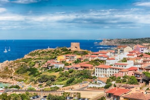 Un pueblo costero con una fortaleza destacada, edificios coloridos y una zona de playa.