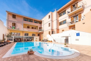 Zona de piscina con terraza solárium, asientos exteriores y comedor cubierto.