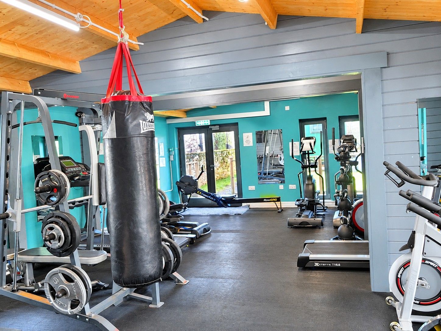 A gym with weightlifting equipment, cardio machines, and a punching bag.