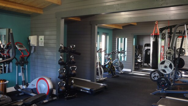 Une salle de sport équipée de divers appareils d’exercice, notamment des tapis de course, des vélos d’appartement et des appareils de musculation.