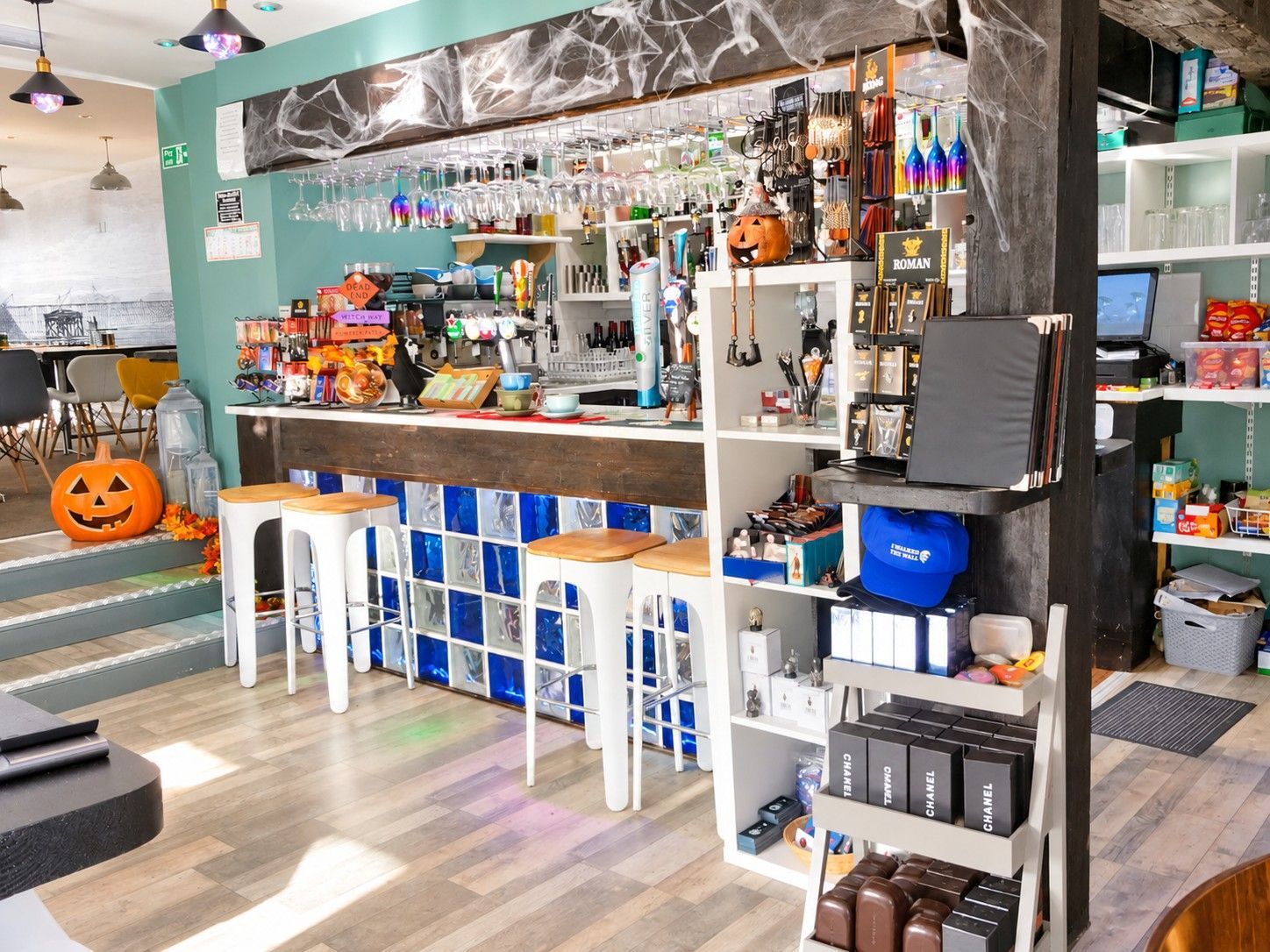 A bar area with stools, shelves stocked with bottles, and Halloween decorations.