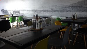 Un restaurant avec des tables et des chaises, une fresque murale et des luminaires suspendus.