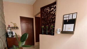 Un pasillo con mostrador de recepción, un calendario en la pared, un felpudo y una planta en maceta.