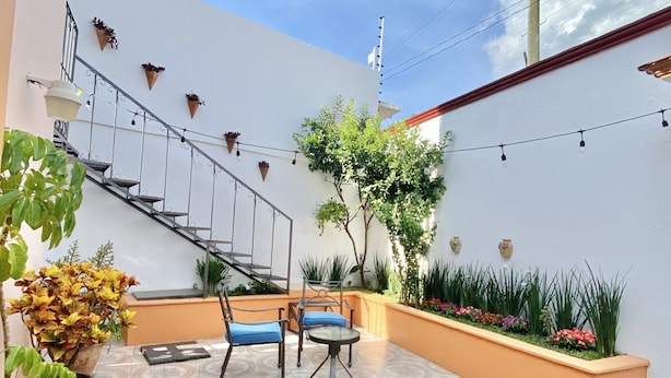 Un amplio patio al aire libre con suelo de baldosas estampadas, una escalera y plantas en macetas.