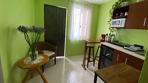 Una cocina compacta con comedor, ventilador de techo y ventana con cortinas.