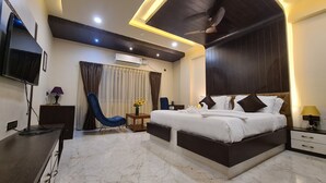 A modern hotel room with a large bed, a flat-screen TV, an air conditioning unit, a ceiling fan, and a marble floor. - Hotel Eden (Karwar)