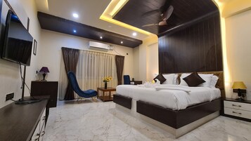 Habitación de hotel moderna con una cama grande, televisión de pantalla plana, aire acondicionado, ventilador de techo y piso de mármol.