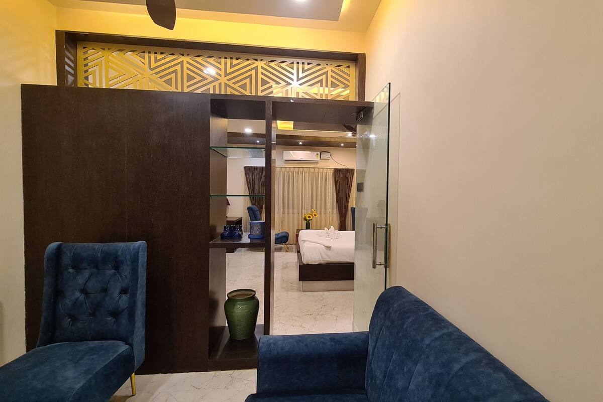 Una habitación de hotel con sofá, una mesita, un jarrón decorativo y una cama.